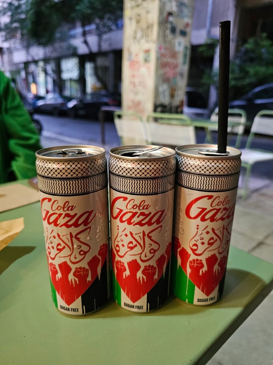 Three Palestinian-design cola cans on a table outside Sumac