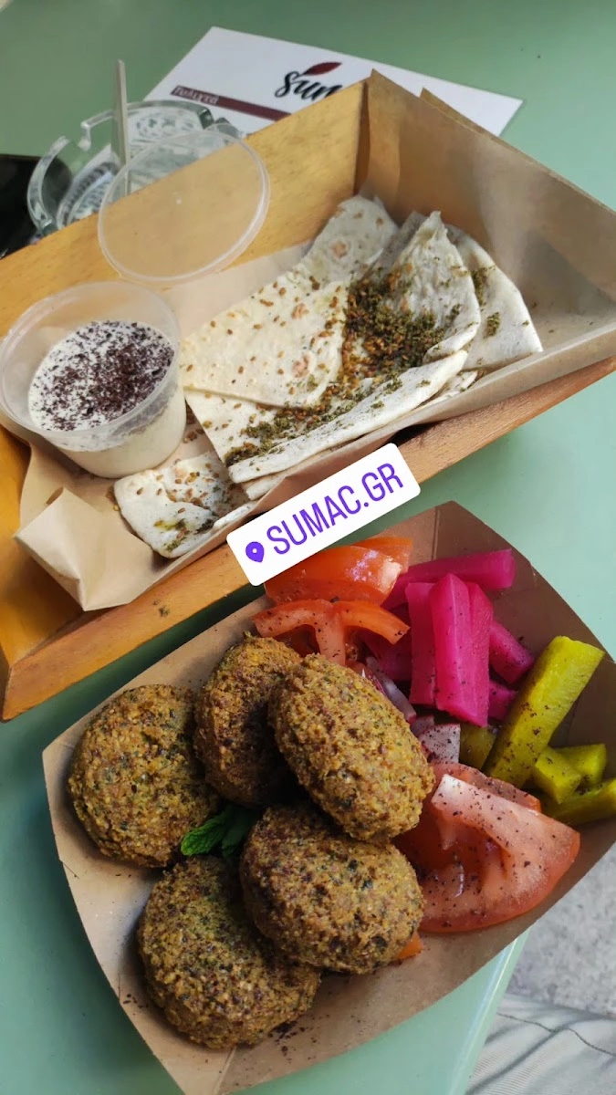 Falafel with colorful pickles, tomatoes, pita bread, and two sauces