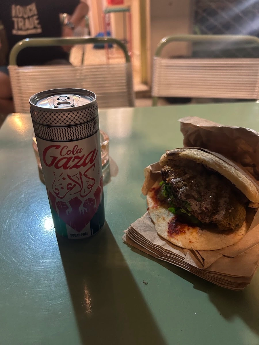 A falafel pita sandwich beside a Palestinian-design cola can